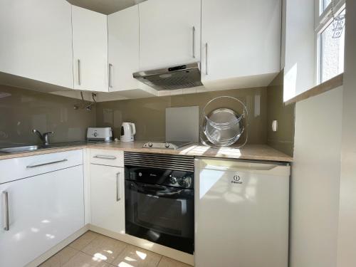 a kitchen with white cabinets and a black oven at Mouraliz Apartments by HD PROPERTIES - Vilamoura Marina in Vilamoura