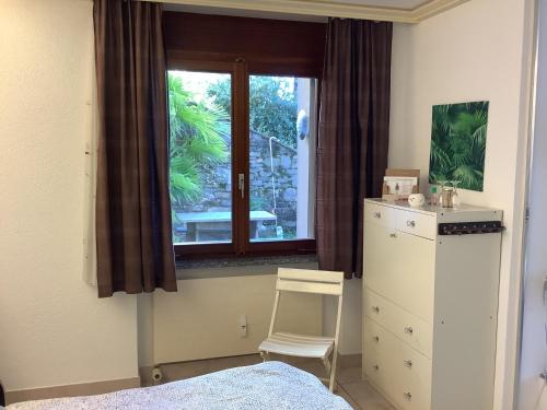 a bedroom with a bed and a dresser and a window at Condominio Andromeda Seeblick in Locarno