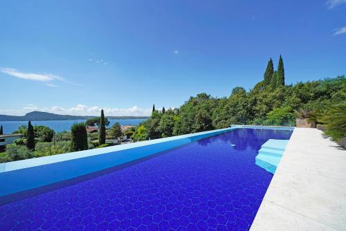 a blue swimming pool with a view of the water at Lamasu RioVerde - Lago di Garda in San Felice del Benaco