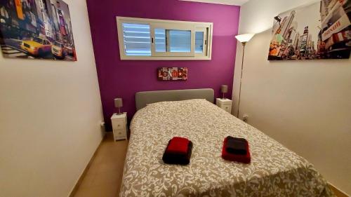 a small bedroom with a bed with two red cushions at Apartments Paradise Lloret in Lloret de Mar