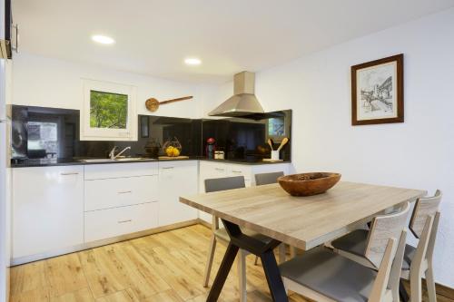 a kitchen with a wooden table and white cabinets at 4LLARS in Beget