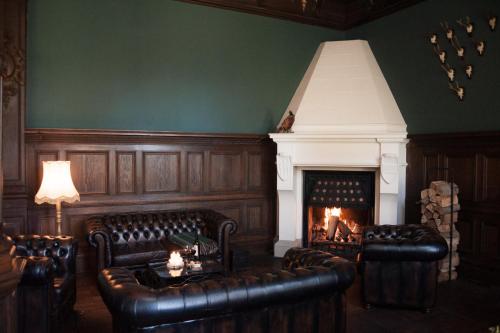 a living room with two leather chairs and a fireplace at Hotel Schloss Neetzow in Neetzow