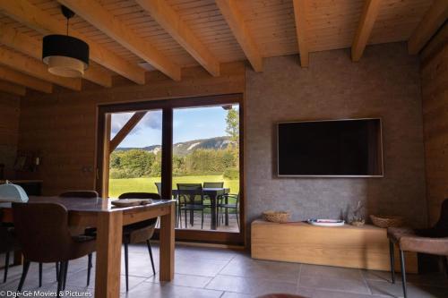 a living room with a television and a table with chairs at Les Jardins du Hérisson Chalet 1 in Bonlieu