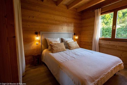 a bedroom with a bed in a log cabin at Les Jardins du Hérisson Chalet 1 in Bonlieu