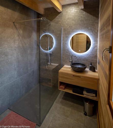 une salle de bain avec une douche en verre avec un lavabo dans l'établissement Les Jardins du Hérisson Chalet 1, à Bonlieu