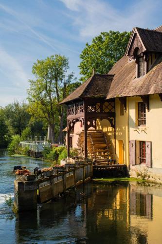 a building on the water next to a river at Moulin de Fourges in Fourges