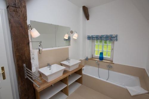 a bathroom with two sinks and a bath tub at Reetdachkate Kiekut - a61544 in Altenhof