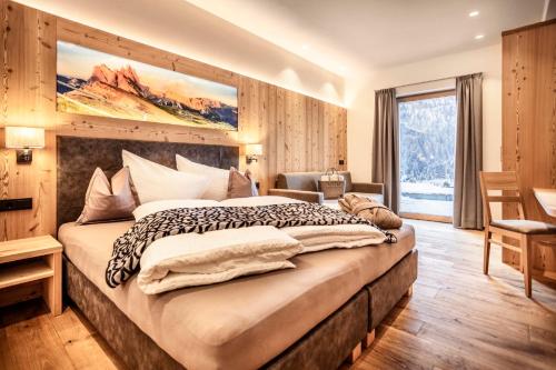 una camera da letto con un letto grande e una grande finestra di Luxury Chalet Plazola a Selva di Val Gardena
