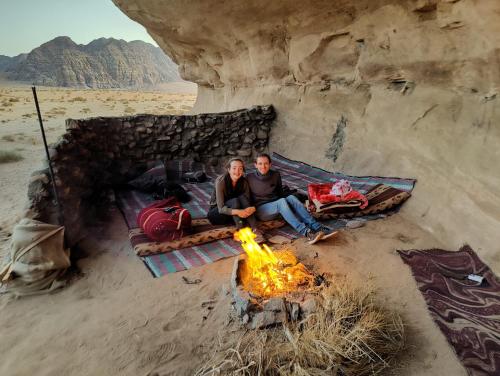 ワディ・ラムにあるGo bedouin campのキャンプファイヤーの横に座っている男女