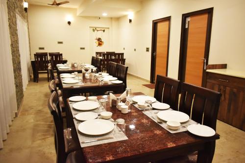 a dining room with a long table with white plates at Captains Paradise Luxury Resort at Mukteshwar Hill Station in Mukteswar