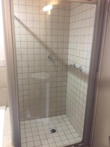 a shower with a glass door in a bathroom at Mabungubwe Hotel Apartments - Home Away from Home in Johannesburg