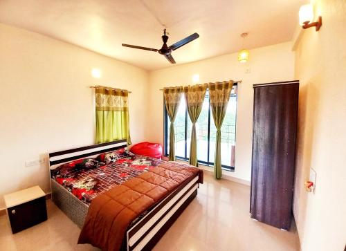 a bedroom with a bed and a ceiling fan at Dadaji Villa in Panchgani