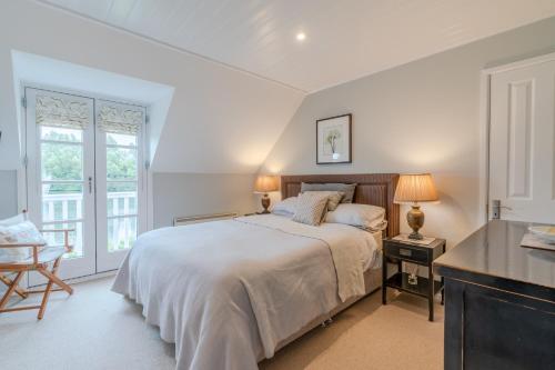 a white bedroom with a bed and a window at Mayfly Lodge in South Cerney