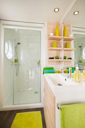 La salle de bains est pourvue d'une douche et d'un lavabo blanc. dans l'établissement Camping Paris Beau Village, à Villiers-sur-Orge