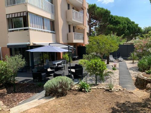 a building with a patio with tables and an umbrella at Les Enganes in Fréjus