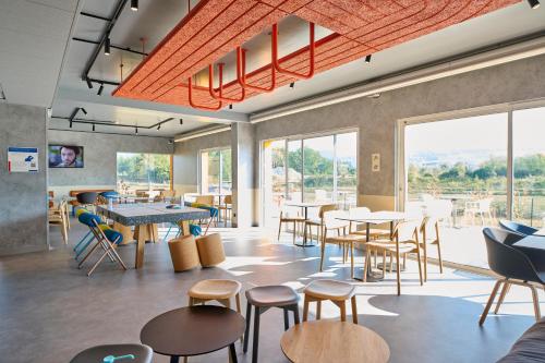 un restaurant avec des tables et des chaises et de grandes fenêtres dans l'établissement Ibis Budget Nangy Annemasse, à Nangy