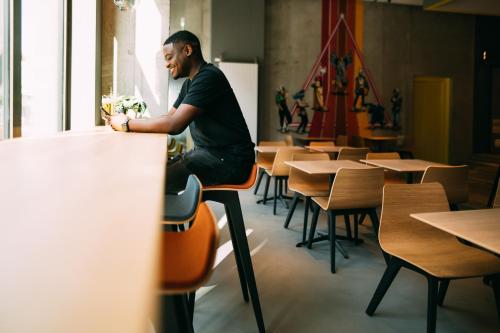 a man sitting on a table in a room with tables and chairs at CAB20 in Hamburg