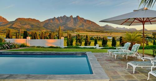 a pool with chairs and an umbrella and mountains at Val Du Charron Wine & Leisure Estate in Wellington