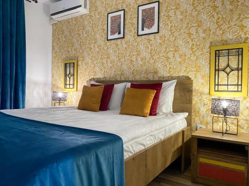 a bedroom with a bed with red and yellow pillows at Autumn Bliss Apartment in Timişoara