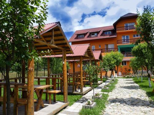ein Resort mit Holztischen und einem Gebäude in der Unterkunft Floare de Colt Petrosani in Petroşani