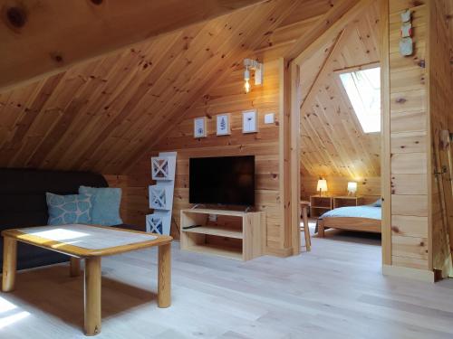 a room in a log cabin with a television and a bed at Le Carré de Bois in Briançon