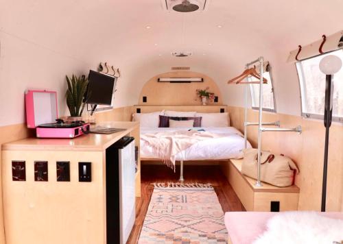 Un dormitorio con una cama y un escritorio en un autobús en Amigo Motor Lodge, en Salida