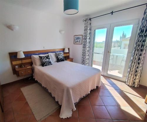 een slaapkamer met een bed en een grote glazen schuifdeur bij Casa Morgado in Tavira