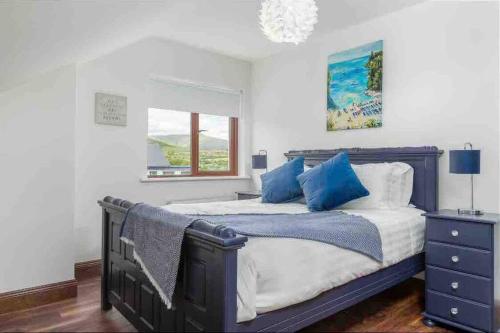 a bedroom with a bed with blue pillows and a window at Wonderful Coastal home in Dingle town in Dingle