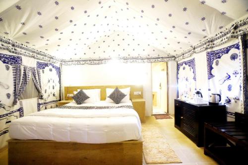 a bedroom with a bed with blue and white wallpaper at Excellent Desert Safari camp in Sām