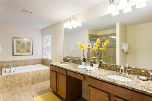 uma casa de banho com 2 lavatórios, uma banheira e um tubermottermott em 6Br 6Bath Pvt Home Pool 10min Disney 3282ft em Kissimmee
