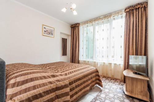 Un dormitorio con una cama y un televisor y una ventana. en Vieno miegamojo apartamentai Juodkrantėje, en Juodkrantė