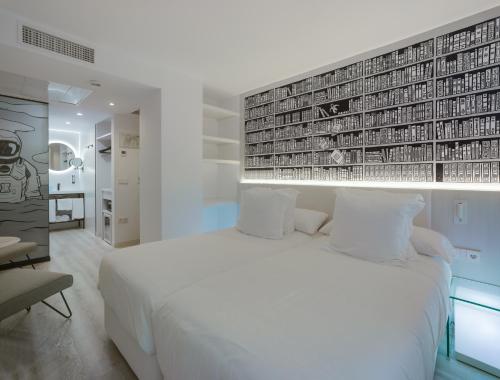a bedroom with a white bed and a wall of books at Dormirdcine Alicante in Alicante