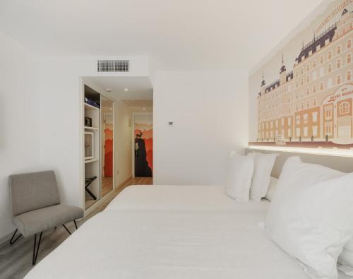 a white bedroom with a bed and a chair at Dormirdcine Alicante in Alicante