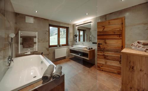 een grote badkamer met een bad en een wastafel bij Alpin Apartement G'ret in Flachau