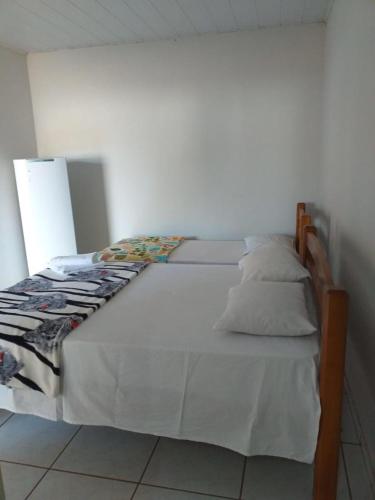 - un lit avec des draps et des oreillers blancs dans l'établissement Pousada Mato Grosso, à Nobres