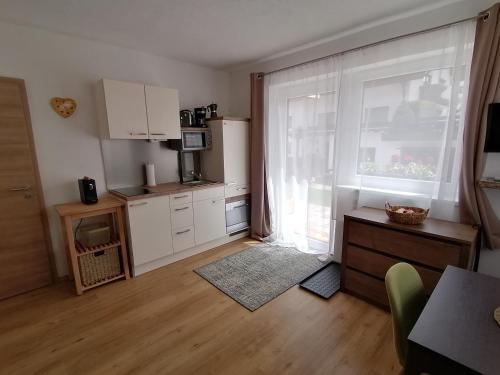 a kitchen with white cabinets and a large window at Bergperle Apartments & Mountain Sport in Fliess