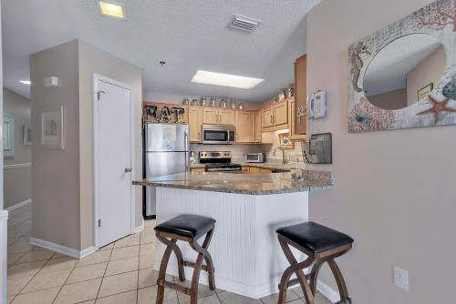 a kitchen with a counter and two bar stools at Phoenix 6 Unit 1209 in Orange Beach