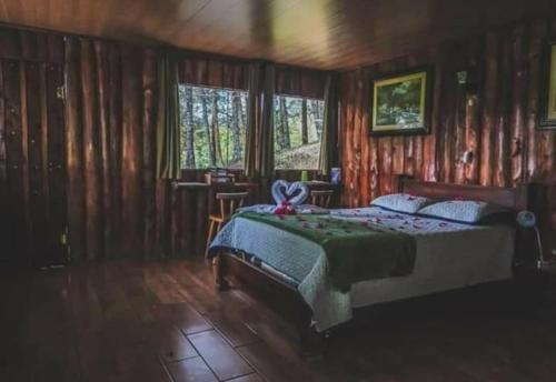 a bedroom with a bed in a room with wooden walls at Cabañas Cerro Verde Lodge y Spa in Cartago