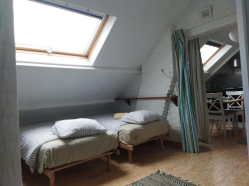 a attic room with two beds and a window at Beatrice's gardens in Nivelles
