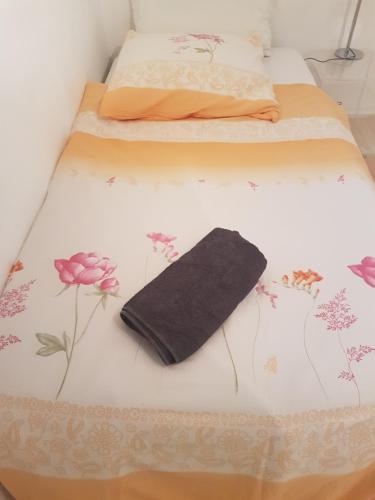 ein Bett mit einer schwarzen Decke und Blumen darauf in der Unterkunft Zimmer 1 nahe Thoraxklinik - Bad und Küche geteilt in Heidelberg