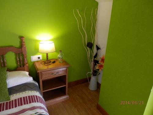 a green bedroom with a bed and a table with a lamp at Hostal Ezkurra in Ezkurra