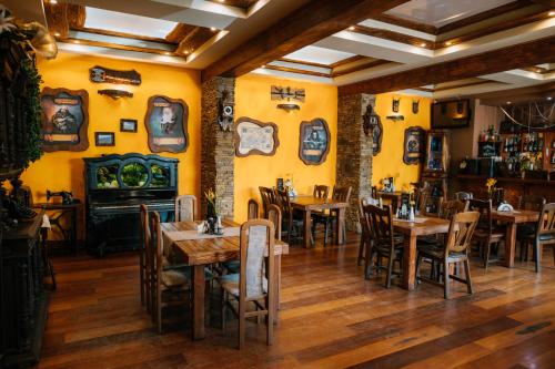 um restaurante com mesas e cadeiras de madeira e paredes amarelas em Kasztelan em Krosno