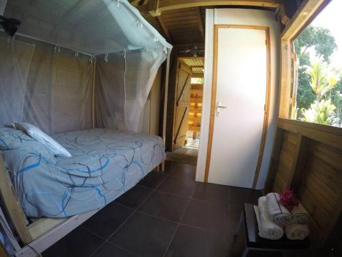 ein Schlafzimmer mit einem Himmelbett in einem Zimmer in der Unterkunft RARE : Bungalow bois avec piscine privée , Gîte ti plaisir in Le Moule
