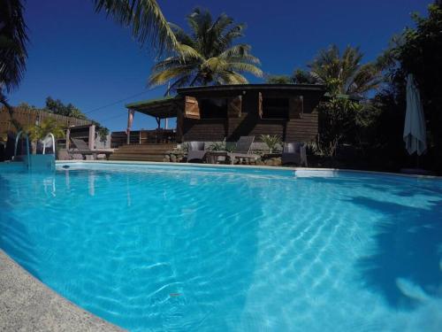 a large blue swimming pool in front of a house at RARE : Bungalow bois avec piscine privée , Gîte ti plaisir in Le Moule