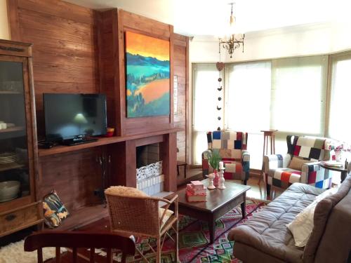 un soggiorno con un divano e una TV di FLAT DE CHARME RÚSTICO EM GRAMADO a Gramado