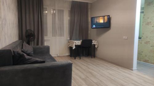 sala de estar con sofá y TV en la pared en Apartment near city center on Peremohy Avenue 46, en Cherníhiv