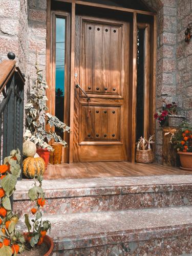 a wooden front door of a house with flowers on the steps at Bujtina Liana Voskopoje in Voskopojë