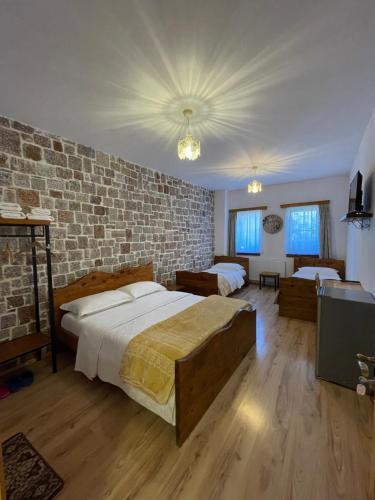 a bedroom with two beds and a brick wall at Bujtina Liana Voskopoje in Voskopojë