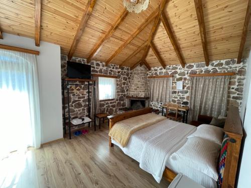 a bedroom with a bed and a stone wall at Bujtina Liana Voskopoje in Voskopojë