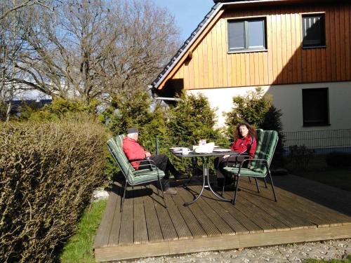 two people sitting at a table on a deck at Tor zum Darss in Pruchten